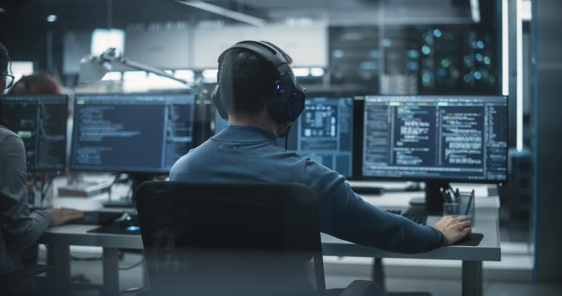 A cybersecurity specialist sits at his workstation inside an IT room.