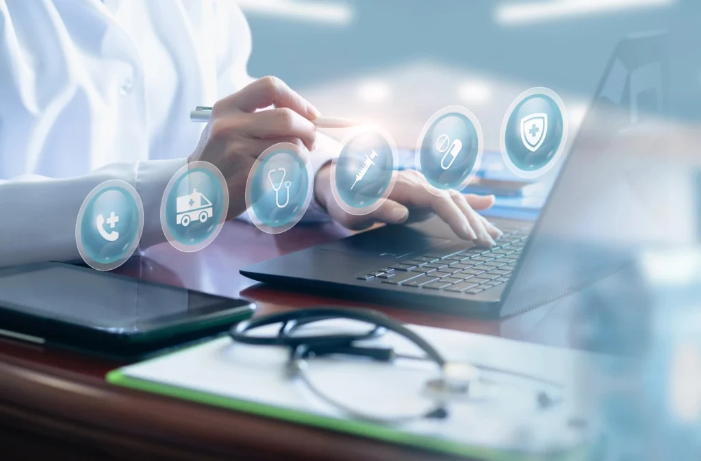 Several healthcare icons hover above a medical coder's hands and laptop.
